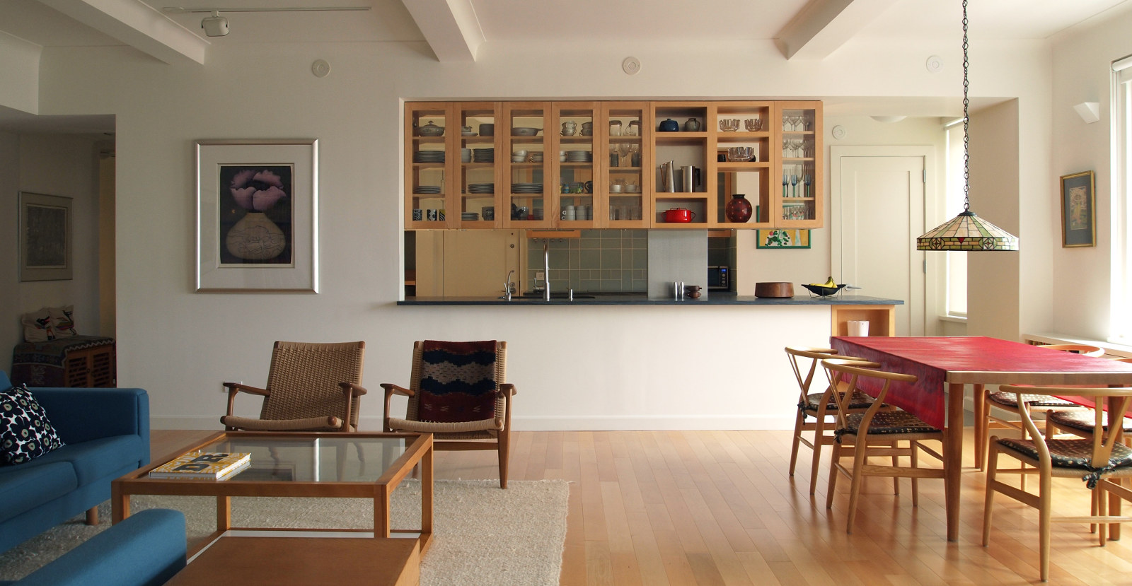 Open kitchen with double-sided hanging maple-framed glass cabinets; view from living room and dining room.