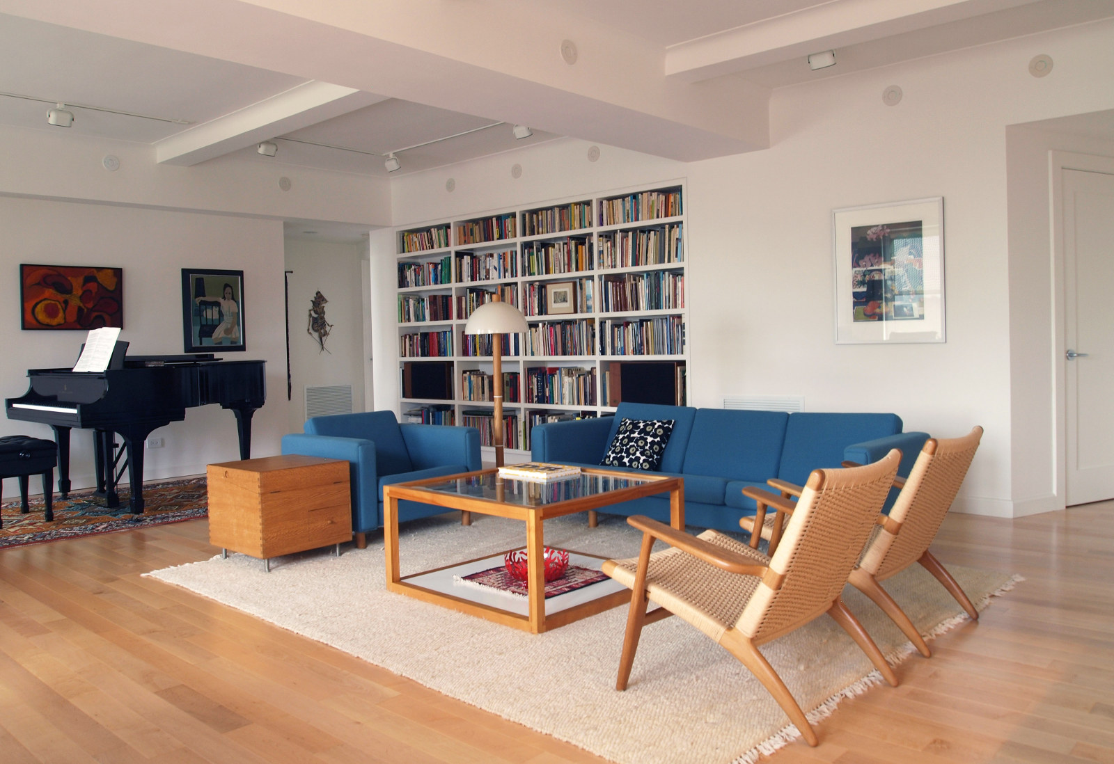 Living room with mid-century modern furniture, built-in custom bookshelves, and piano.