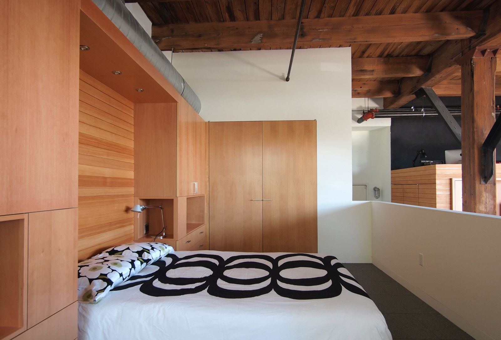 Loft renovation, with open bedroom loft and custom built-in cabinetry around bed.