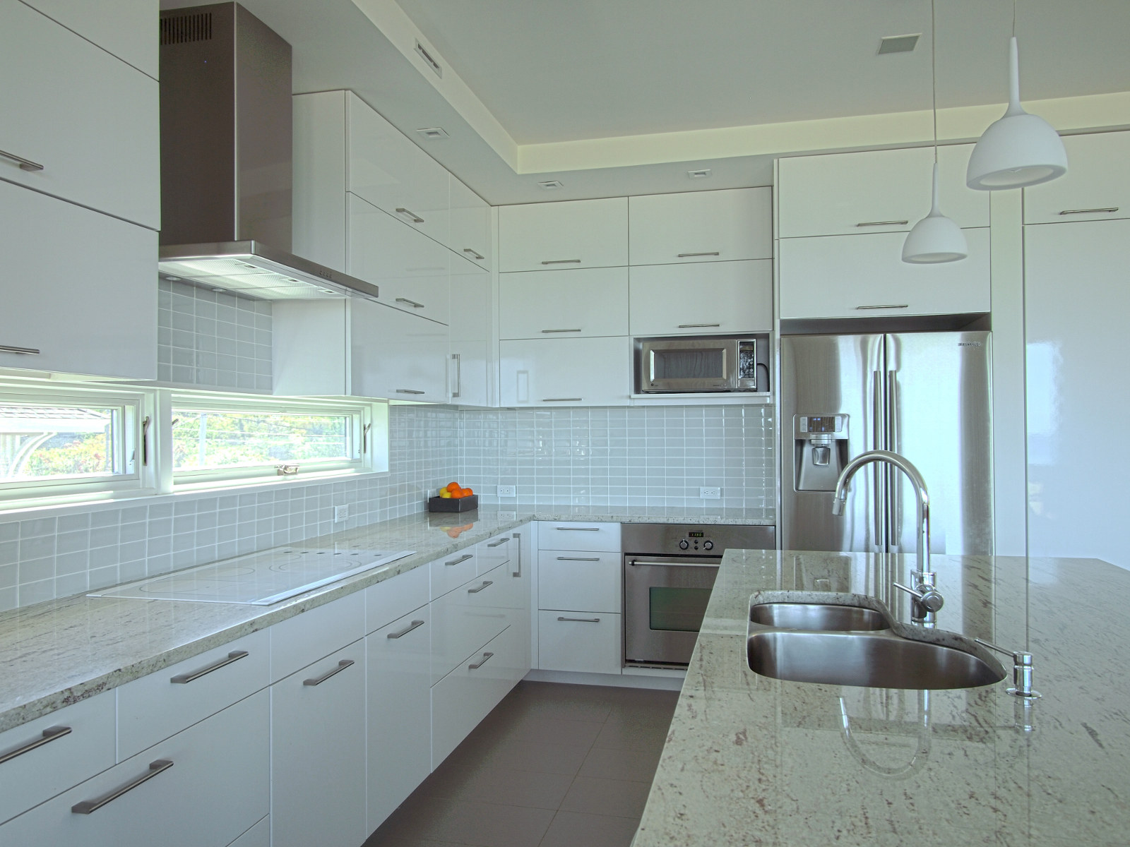 Modern kitchen with white cabinets, stainless steel appliances, glass tile backsplash, and granite counters.