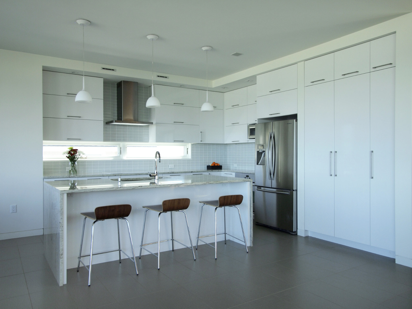 Modern kitchen with white cabinets, stainless steel appliances, glass tile backsplash, and granite counters.