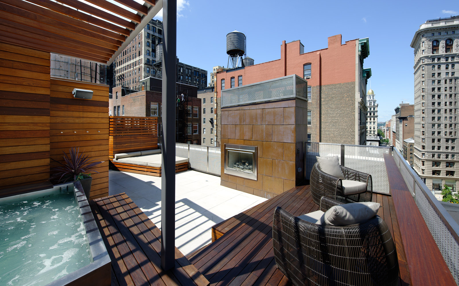 Modern roof deck in New York City with hot tub, ipe decking and trellis, and copper fireplace