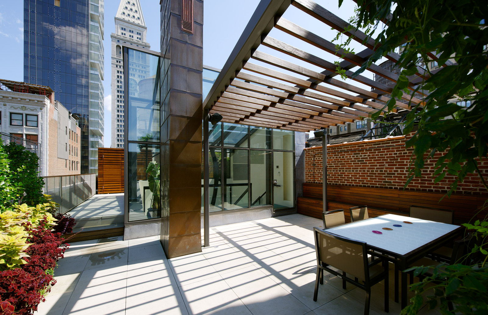 Modern roof deck in New York City with ipe and steel trellis, stone pavers, and planters.