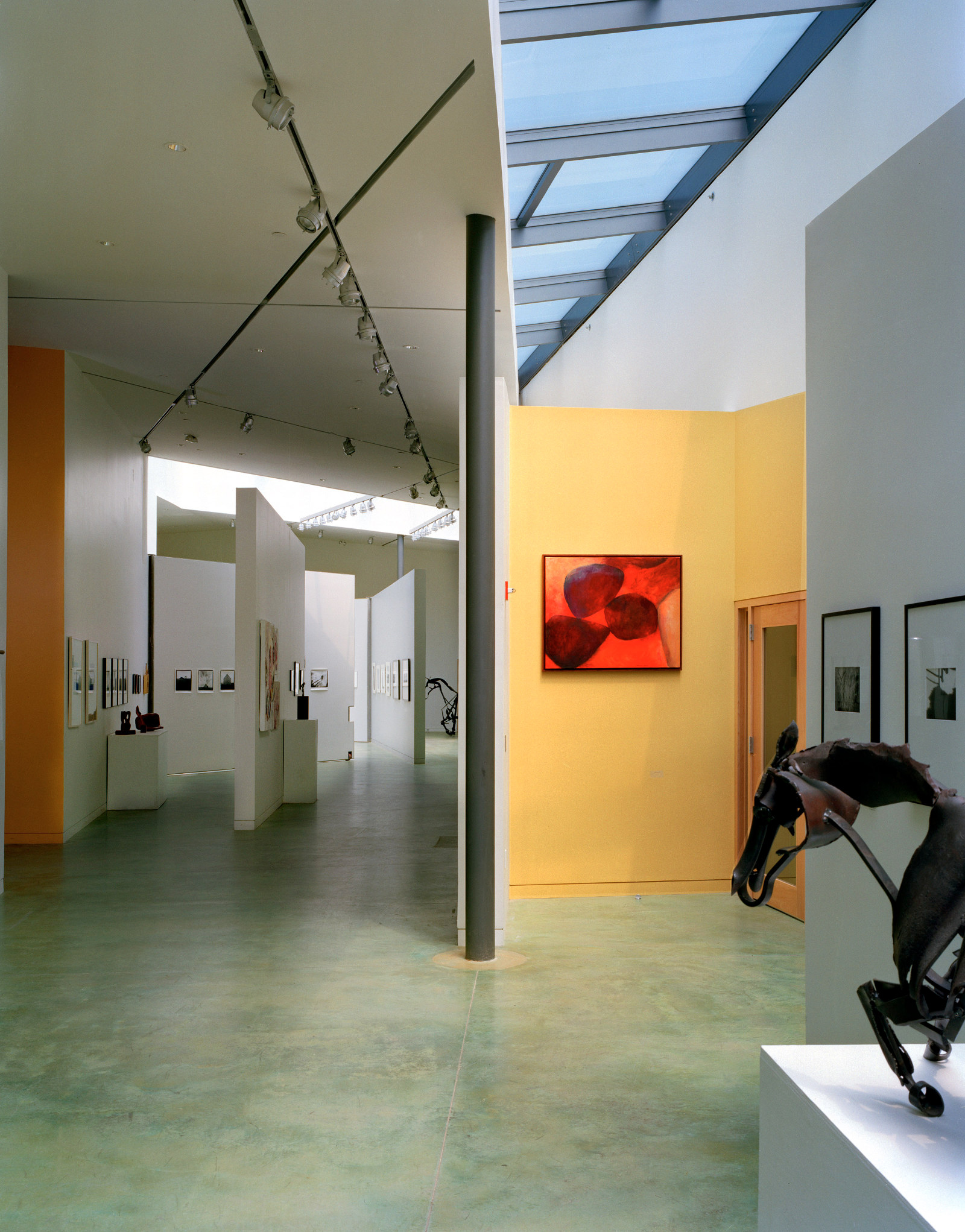 Light-filled corridor and gallery space at The Putney School, with skylights and green-stained concrete floor.