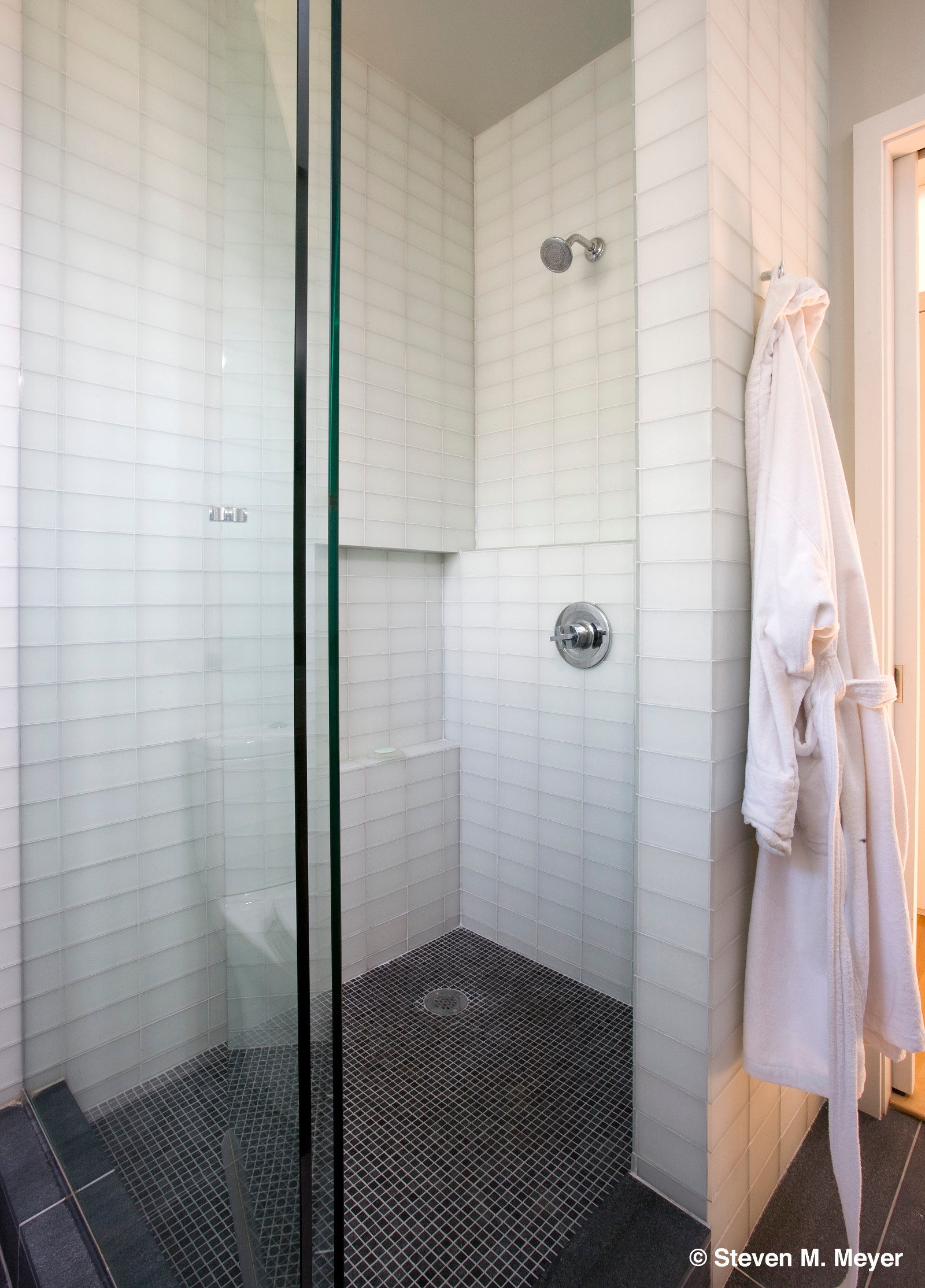 Modern shower with white glass tile, gray stone floor.