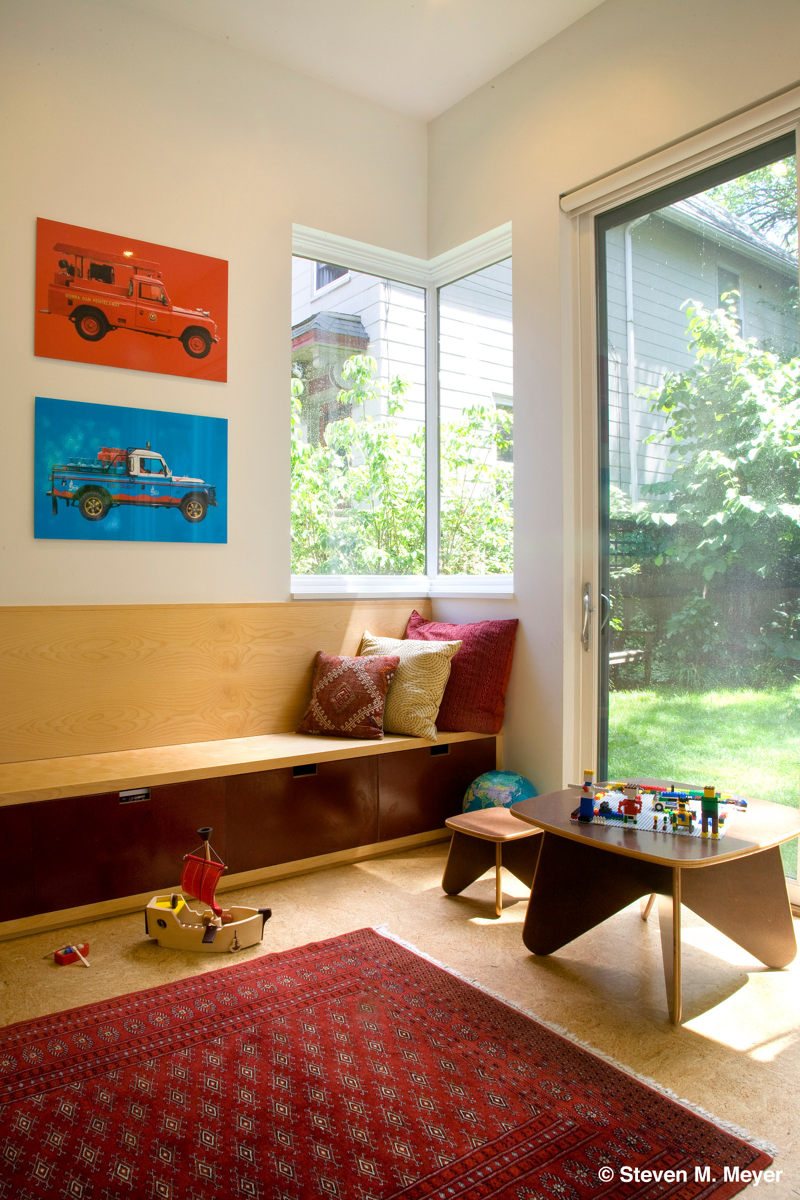 Sunroom or play room with custom built-in bench, cork floor, and corner window.