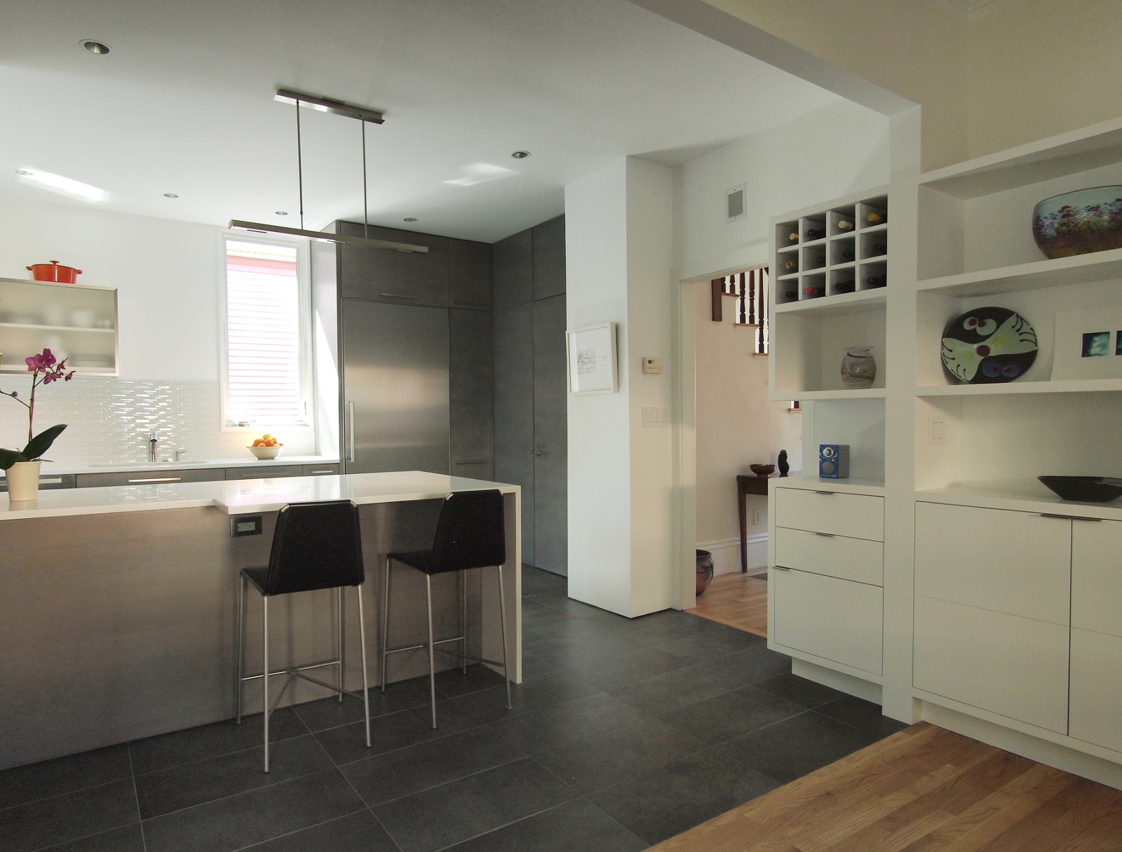 Modern custom kitchen with gray cabinets, stainless steel appliances, white Caesarstone countertops, and white custom storage cabinet.