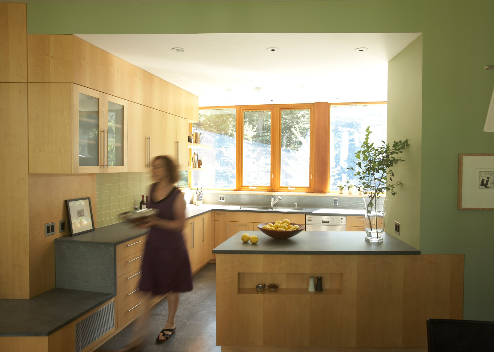 Modern kitchen with maple cabinets, stone counter, and corner window.